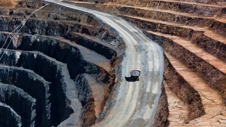 Operação de mineração em cava aberta demonstrando bancadas e engenharia geotécnica para estabilização de taludes.