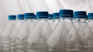 Garrafas plásticas transparentes com tampas azuis, representando envase e produção de água mineral.